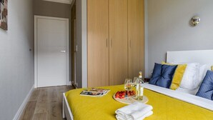 Quarto com cama, mesa de cabeceira com revista, garrafa e copos.
