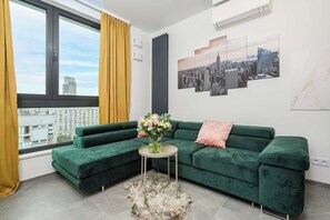 Ein modernes Wohnzimmer mit einem grünen Sofa, einem kleinen runden Tisch und einer Blumenvase.