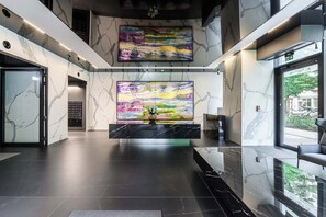 A modern lobby with marble flooring, a reception desk, and a large abstract painting. - Lush Home near Varso Tower (Warszawa)
