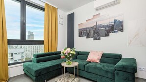 A modern living room with a green sofa, a small round table, and a vase of flowers. - Lush Home near Varso Tower (Warszawa)