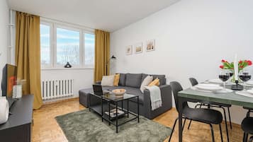 A modern living room with a sofa, coffee table, and dining area.