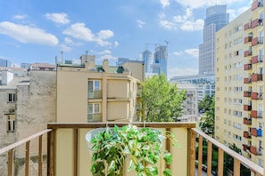 A balcony with a potted plant, a view of a cityscape with modern buildings, and a clear sky. - Apartment with Private Balcony (Warszawa 2)