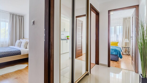 A modern hotel room with a bed, a bathroom, and a view of the adjacent room. - Apartment with Private Balcony (Warszawa 2)