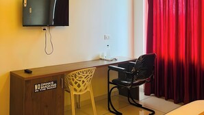 A hotel room with a desk, a television mounted on the wall, a red curtain, and a sign on the desk stating 'NO DRINKS SMOKING IN THE ROOM'. - MASBAH RESIDENCY (Mananthavady)
