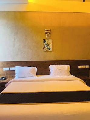 A hotel room with a bed, a nightstand with a phone, and a wall-mounted light fixture. - MASBAH RESIDENCY (Mananthavady)