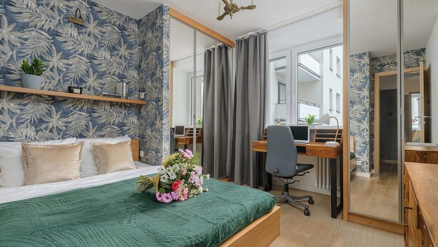 A hotel room with a bed, a desk, a chair, a mirror, and a window. - Beachfront Villa with Panoramic Sea Views (Warszawa 2)
