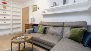 A living room with a sofa, a small table, and a bookshelf. - Beachfront Villa with Panoramic Sea Views (Warszawa 2)