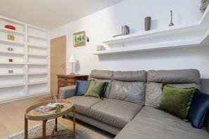 Ein Wohnzimmer mit einer Couch, einem kleinen Tisch und einem Bücherregal.