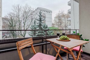 Ein Balkon mit einem Holztisch, Stühlen und einer Schüssel grüner Trauben.