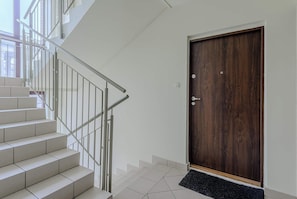 A staircase with metal railings leading to a dark wooden door. - Warsaw Apartment with Panoramic City Views (Warszawa 2)