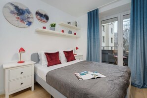 Ein Schlafzimmer mit einem Bett, Nachttischen, einer Zeitschrift und Blick durch ein Fenster.