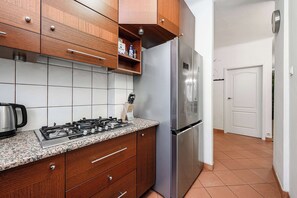 Eine Küche mit Holzschränken, einem Edelstahlkühlschrank, einem Gasherd und einer Kaffeemaschine.