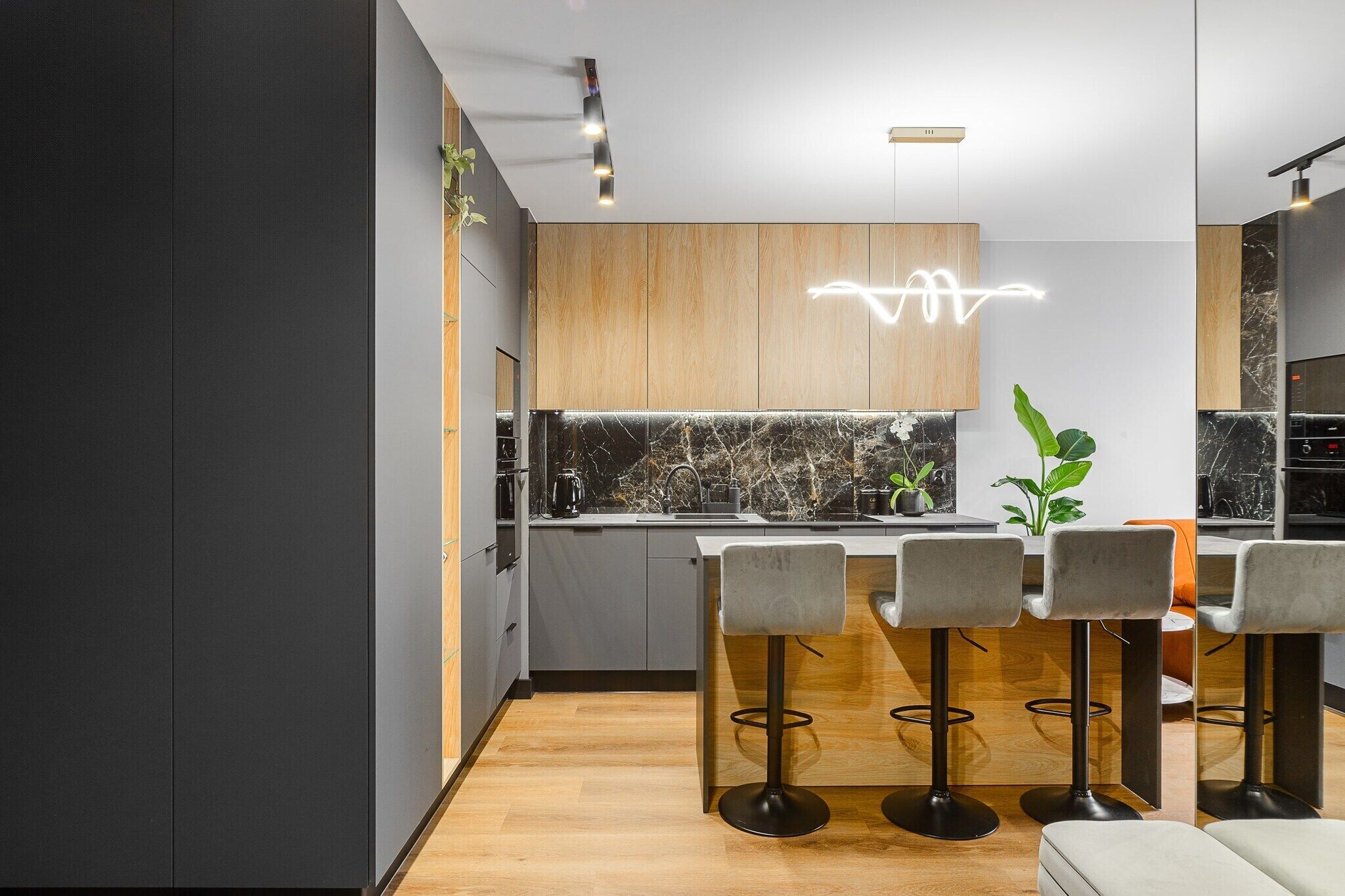 Una cocina moderna con salpicadero de mármol, armarios de madera y una barra con taburetes.