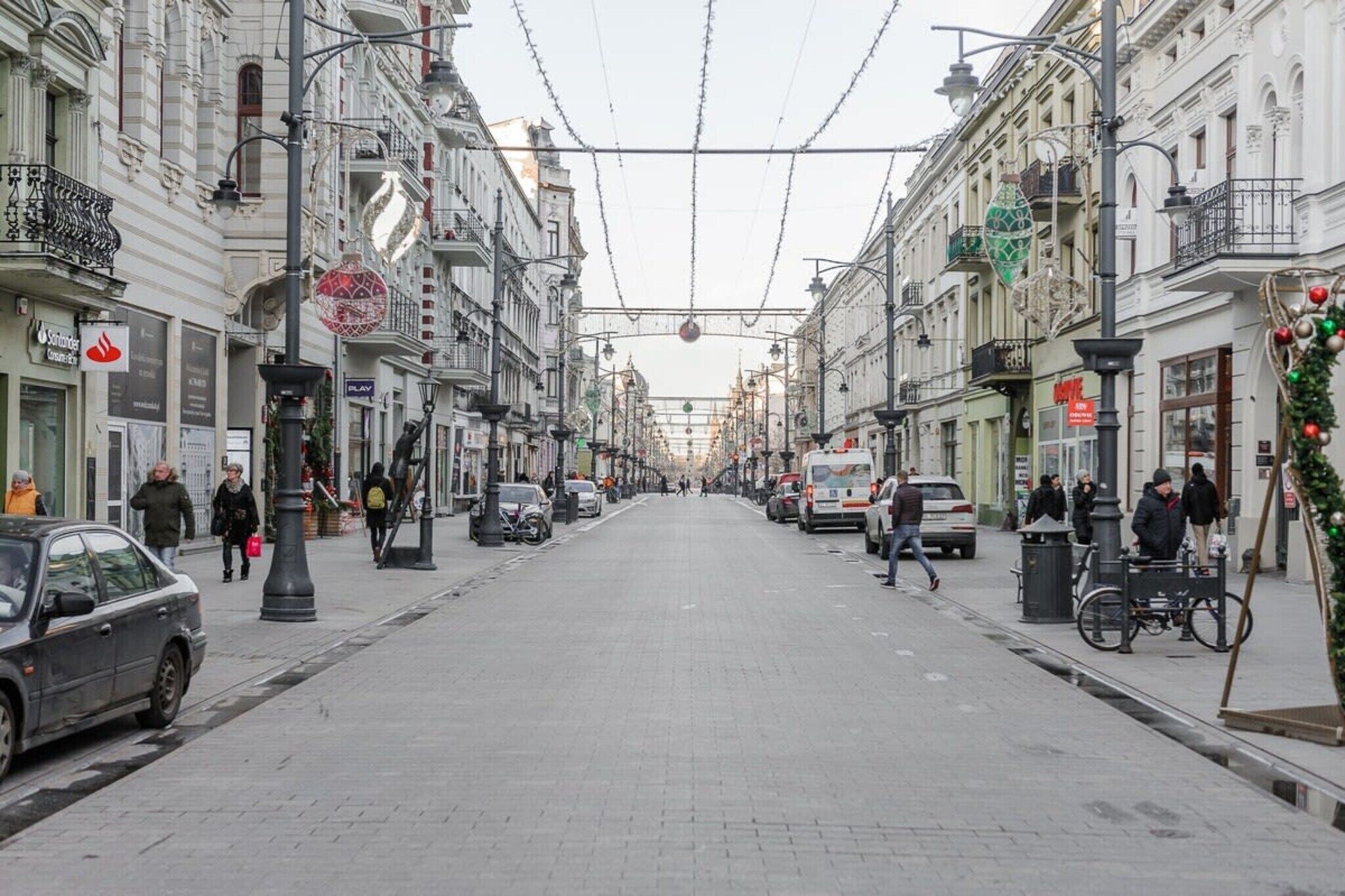 A street lined with historic buildings, a tram, and pedestrians.