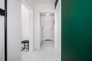 Ein Korridor mit einer grünen Bank, weißen Wänden und einer Tür am Ende.