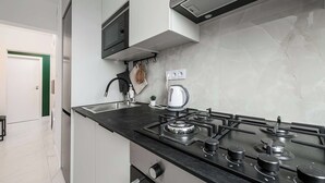 Cozinha moderna com fogão a gás, chaleira e micro-ondas.