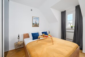 Ein Schlafzimmer mit Bett, Nachttisch, einem Fenster mit Vorhängen und einem Poster an der Wand.