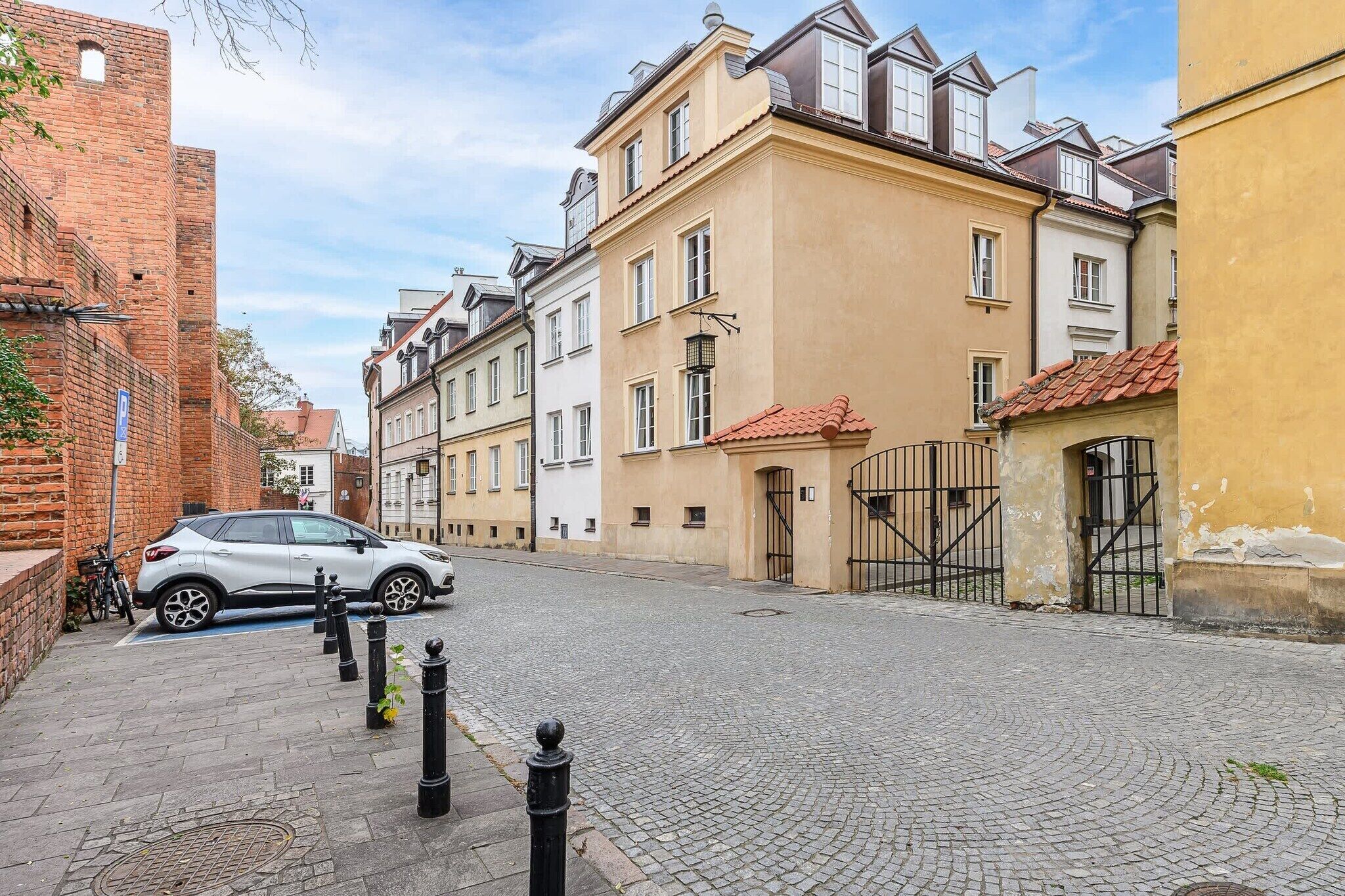 A cobblestone street with historic buildings, a parked car, and a bicycle.