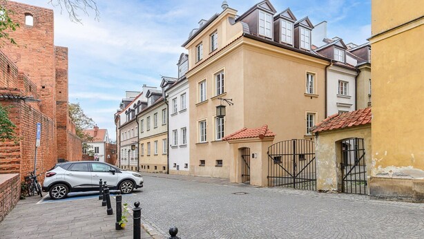 Mukulakivikatu, jota reunustavat historialliset rakennukset, sekä siinä pysäköity auto ja polkupyörä.