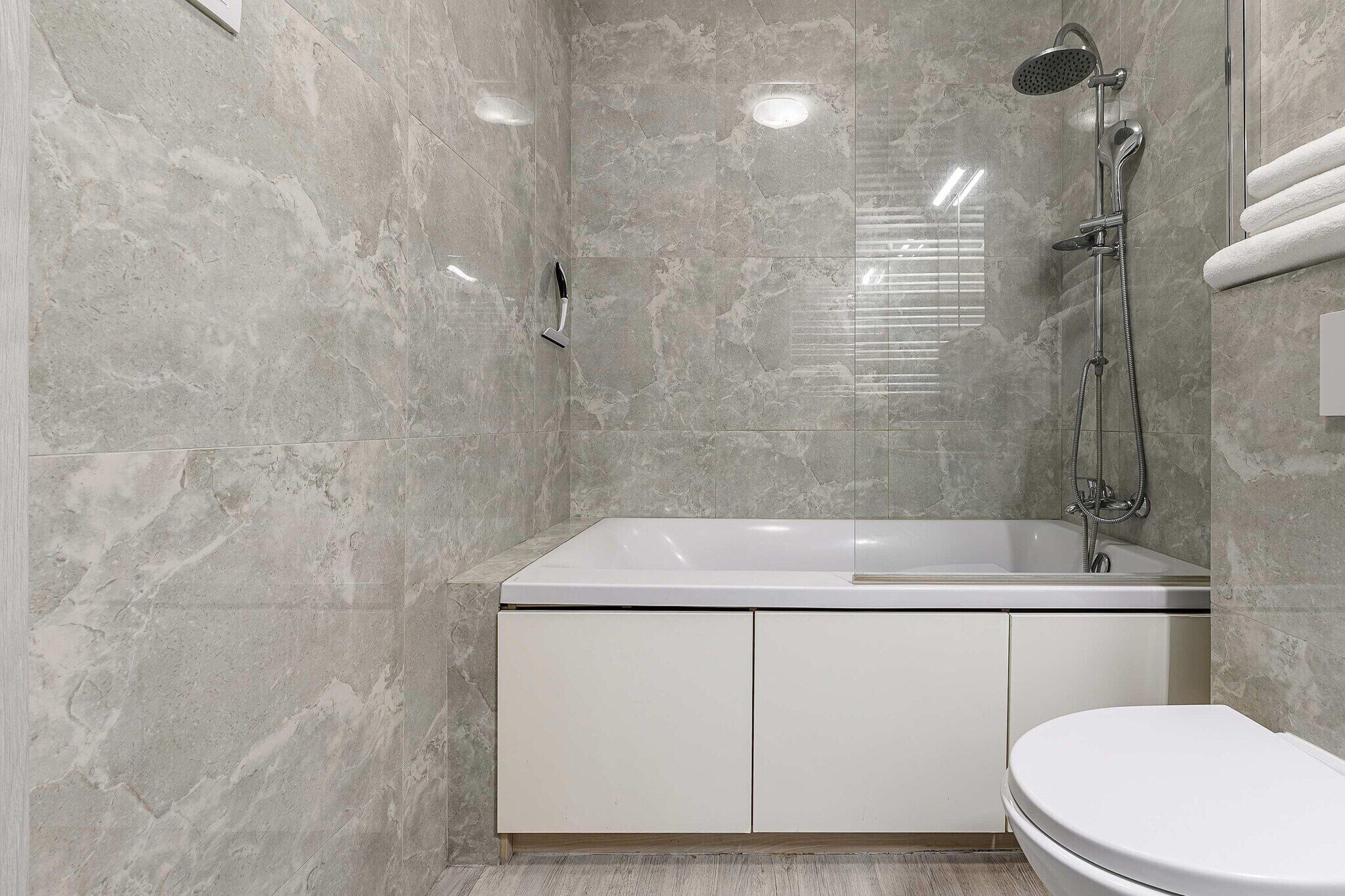 A modern bathroom with a bathtub, shower, and toilet.