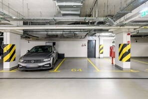 A parking garage with a car parked in a designated space marked with the number 64. - 2-Bedroom Home with Balcony (Warszawa 2)