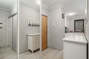 Een badkamer met een houten deur, een spiegel, een klok en een klein kastje met lades.