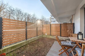 A wooden deck with a table and chairs, a wooden fence, and a building in the background. - 2-Bedroom Home with Balcony (Warszawa 2)