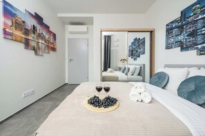 A hotel room with a bed, a bedside table with two glasses of red wine, a tray of grapes, and a white teddy bear. - Warsaw Flat with Balcony (Warszawa)