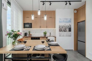 A modern kitchen with wooden cabinets, a built-in microwave, and pendant lighting. - Warsaw Flat with Balcony (Warszawa)