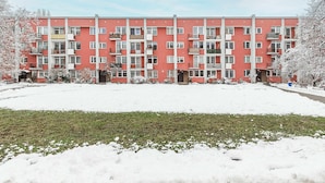 A multi-story residential building with balconies, a flat roof, and a snow-covered ground. - Family Stay on Boguckiego (Warszawa)