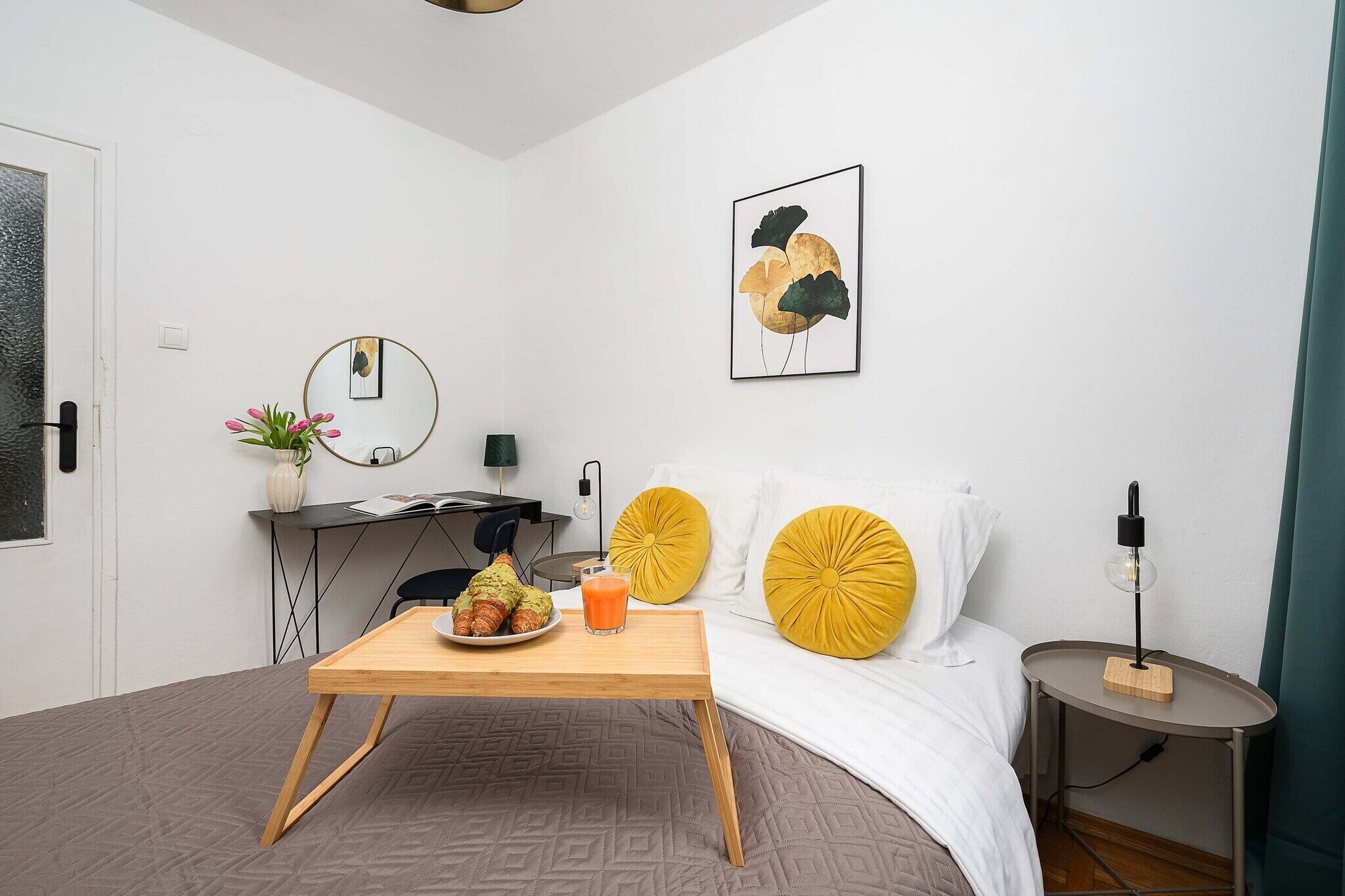 A modern bedroom with a bed, bedside table, and a small desk with a chair.