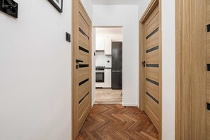 A hallway with wooden doors leading to a kitchen area. - Old Town Apartment for 4 (Warszawa)