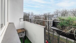 A balcony with a small table, a potted plant, and a view of a cityscape. - Old Town Apartment for 4 (Warszawa)