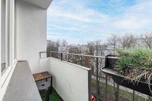 A balcony with a small table, a potted plant, and a view of a cityscape. - Old Town Apartment for 4 (Warszawa)