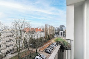 A view from a balcony overlooking a parking area with cars, a building with a red roof, and leafless trees. - Old Town Apartment for 4 (Warszawa)