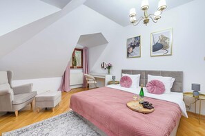 A bedroom with a bed, a chair, a desk, and a window.