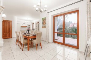 Zona de menjador amb taula i cadires de fusta, un penjallum i una gran porta corredissa de vidre que dona a l'exterior.