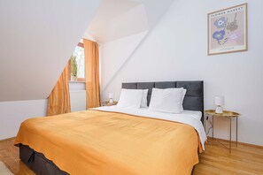 A bedroom with a bed, a nightstand, a lamp, and a framed picture on the wall.