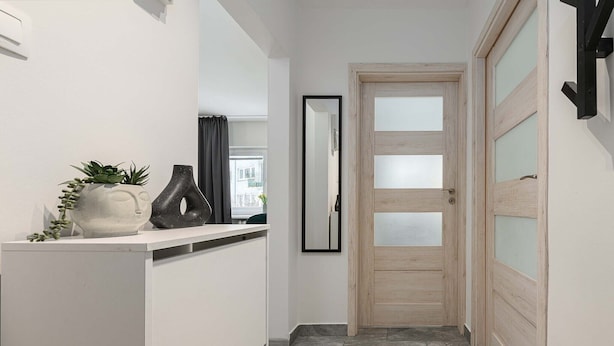 A hallway with a white door, a mirror, and a shelf with decorative items. - Warsay Apartment near Metro (Warszawa 2)