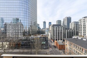 A cityscape with modern high-rise buildings, a clear sky, and a street with parked cars. - Warsaw Flat on Pereca (Warszawa 2)