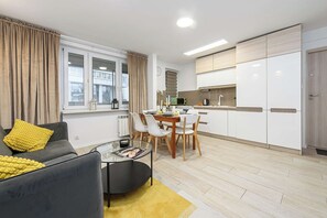 A modern living room with a sofa, coffee table, and dining area with chairs. - Elegant House with Beautiful Seaview (Warszawa 2)