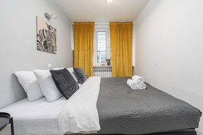 A single bed with a grey quilt, white and black pillows, and a rolled towel on the side. - Elegant House with Beautiful Seaview (Warszawa 2)