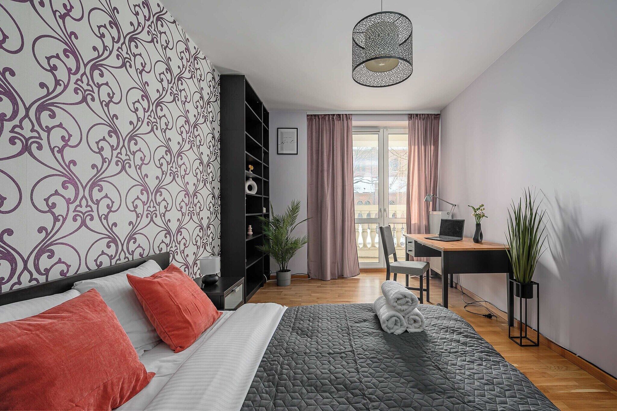 Ett modernt sovrum med en säng, ett skrivbord och en stol. Det finns ett fönster med gardiner, en växt och en lampa.