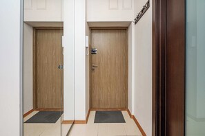 A hallway with two wooden doors, each with a metal handle and a keyhole. - Warsaw Flat with Church Views (Warszawa 2)