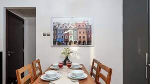 A dining area with a table set for four, chairs, a vase with flowers, and a framed cityscape picture on the wall. - Warsaw Flat with Church Views (Warszawa 2)
