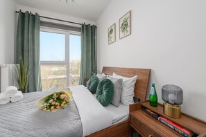 Ein Schlafzimmer mit einem Bett, einem Nachttisch mit Büchern, einer Flasche und einer dekorativen Lampe.