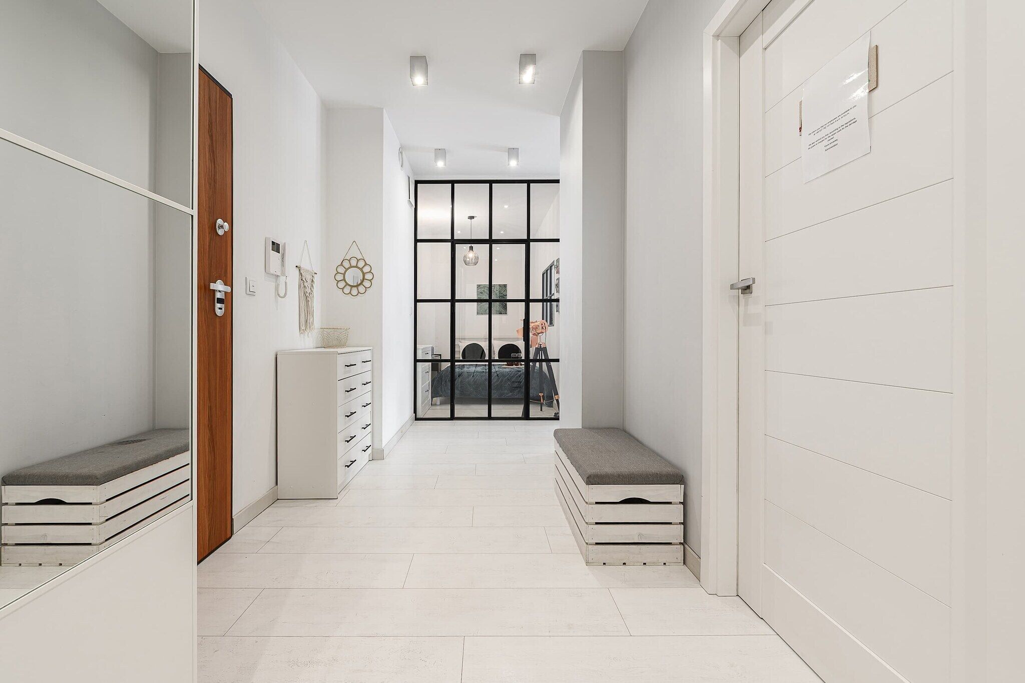 Un pasillo con una puerta de madera, un armario blanco y un banco.