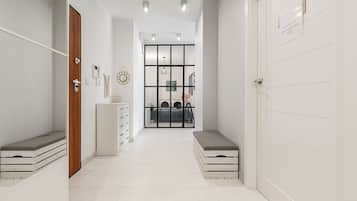 Un pasillo con una puerta de madera, un armario blanco y un banco.