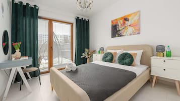 Une chambre à coucher moderne, avec un lit, un bureau, une chaise, une table de chevet et un tableau accroché au mur.