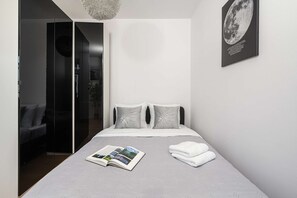 Een moderne slaapkamer met een bed, een tijdschrift en een handdoek op het bed.